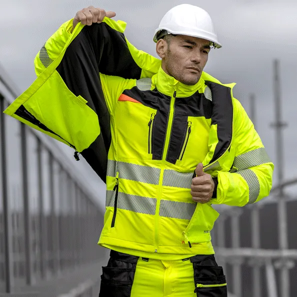 Seorang pekerja konstruksi mengenakan jaket high-visibility Portwest berwarna kuning neon dengan strip reflektif, APD dari distributor resmi Maduma Inti Teknik.